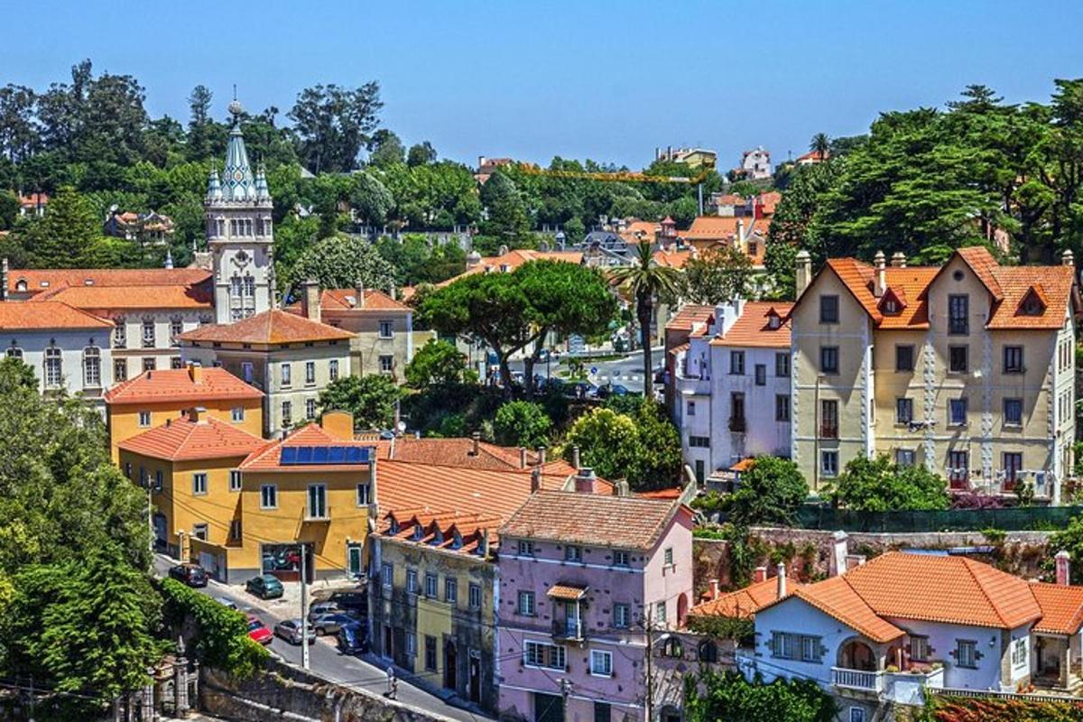 a city with houses and a clock tower on a hill