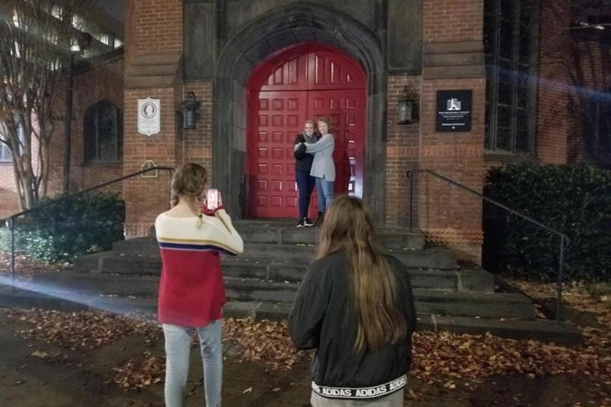 three women standing in front of a red door