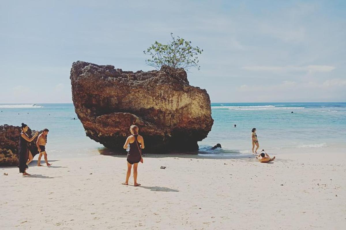 sekumpulan orang di pantai dengan batu besar