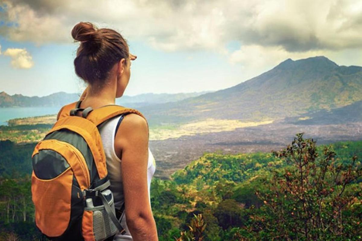 eine Frau mit einem Rucksack steht auf einem Berggipfel