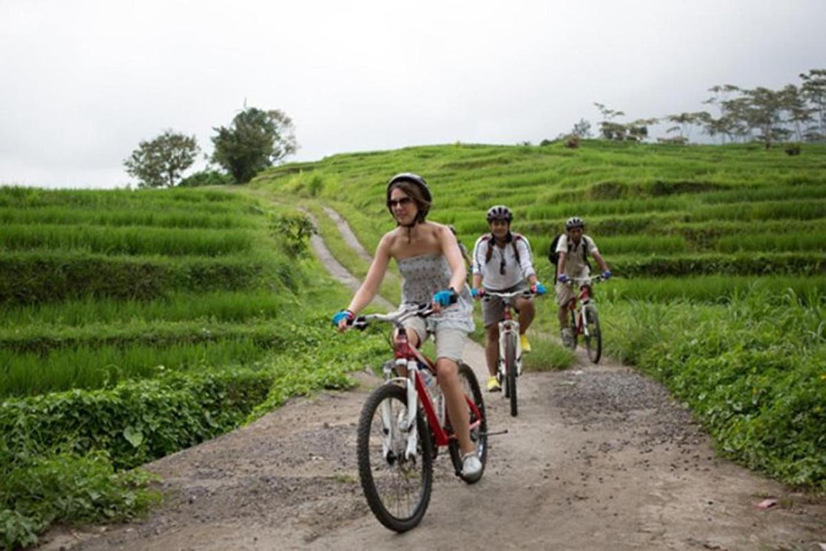 três pessoas andando de bicicleta em uma estrada de terra