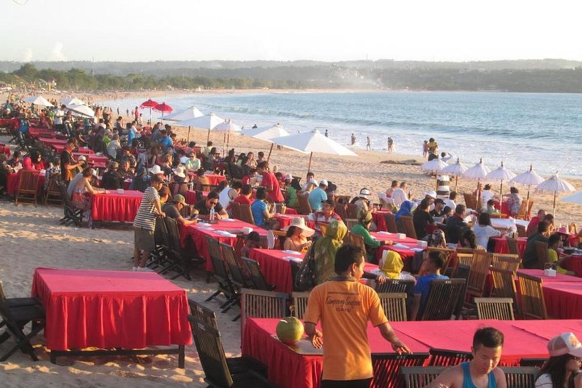 množica ljudi, ki sedijo za mizami na plaži