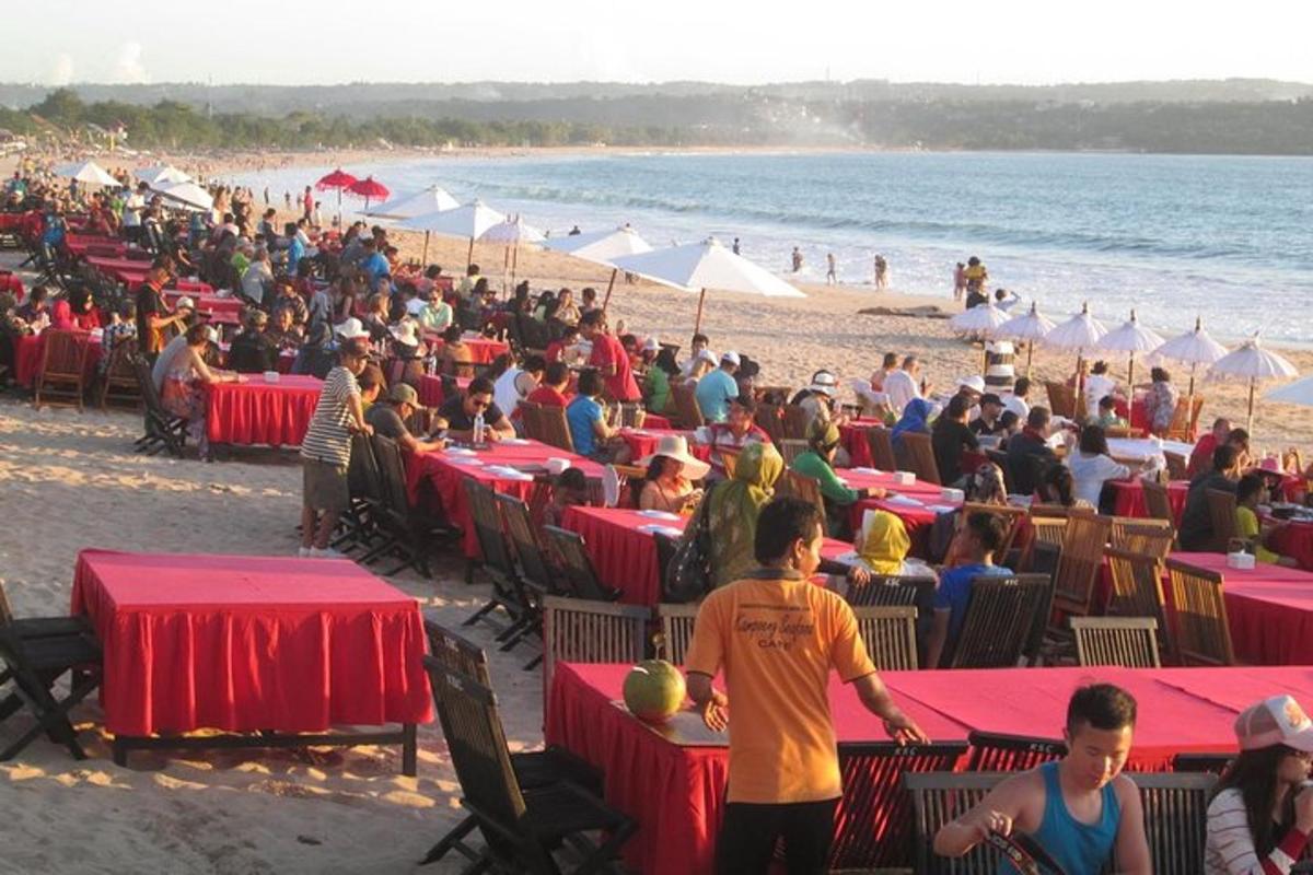 una folla di persone sedute ai tavoli su una spiaggia