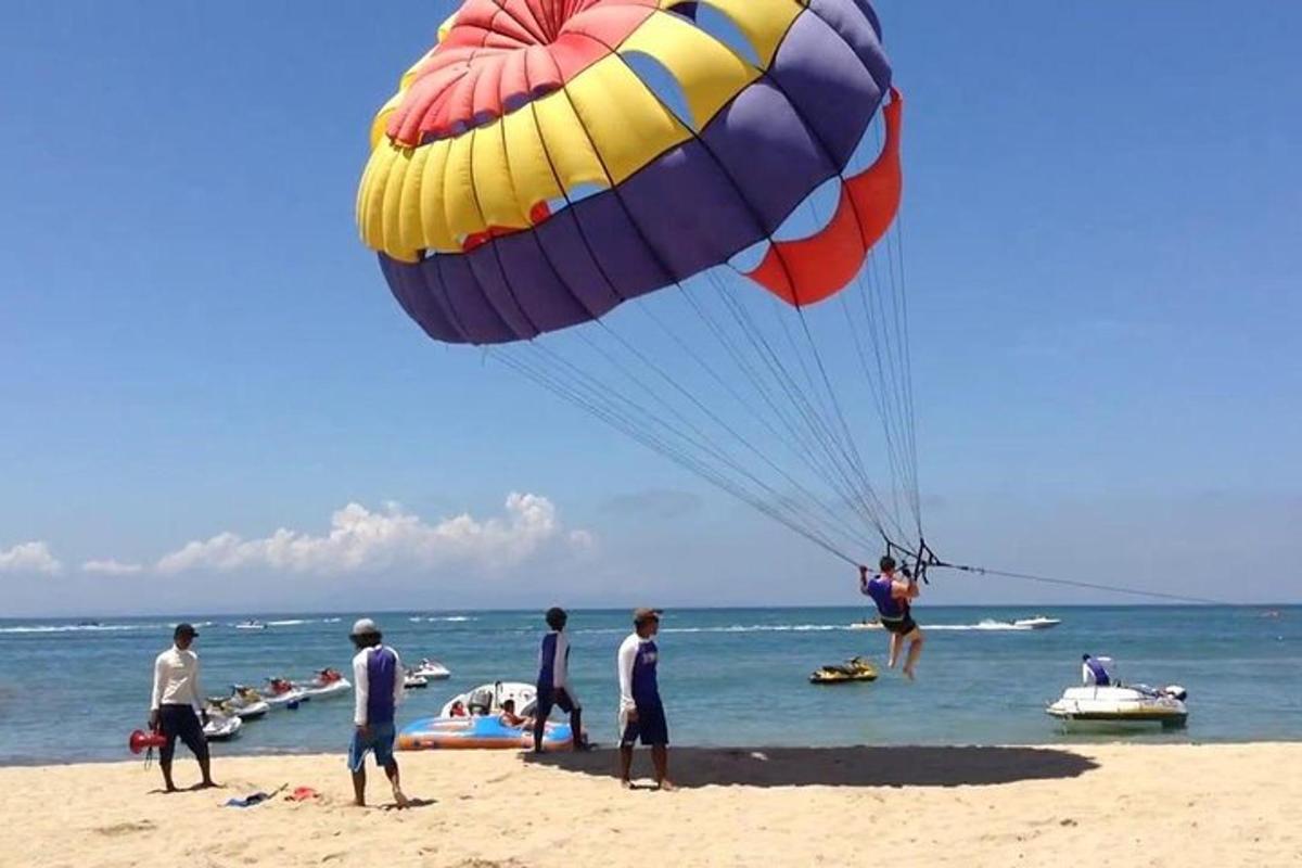 eine Gruppe von Menschen an einem Strand mit einem großen Fallschirm