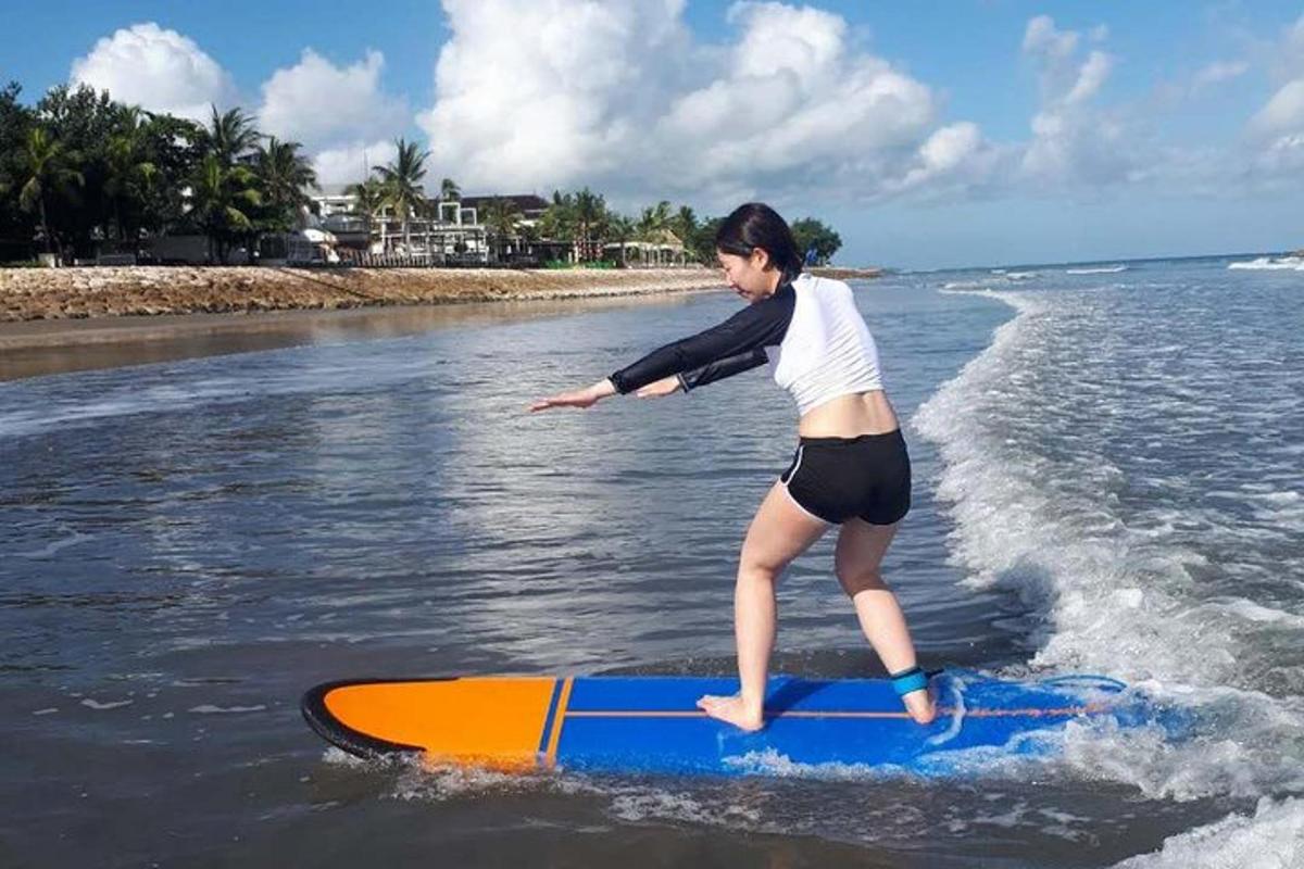 młoda kobieta stojąca na desce surfingowej w wodzie