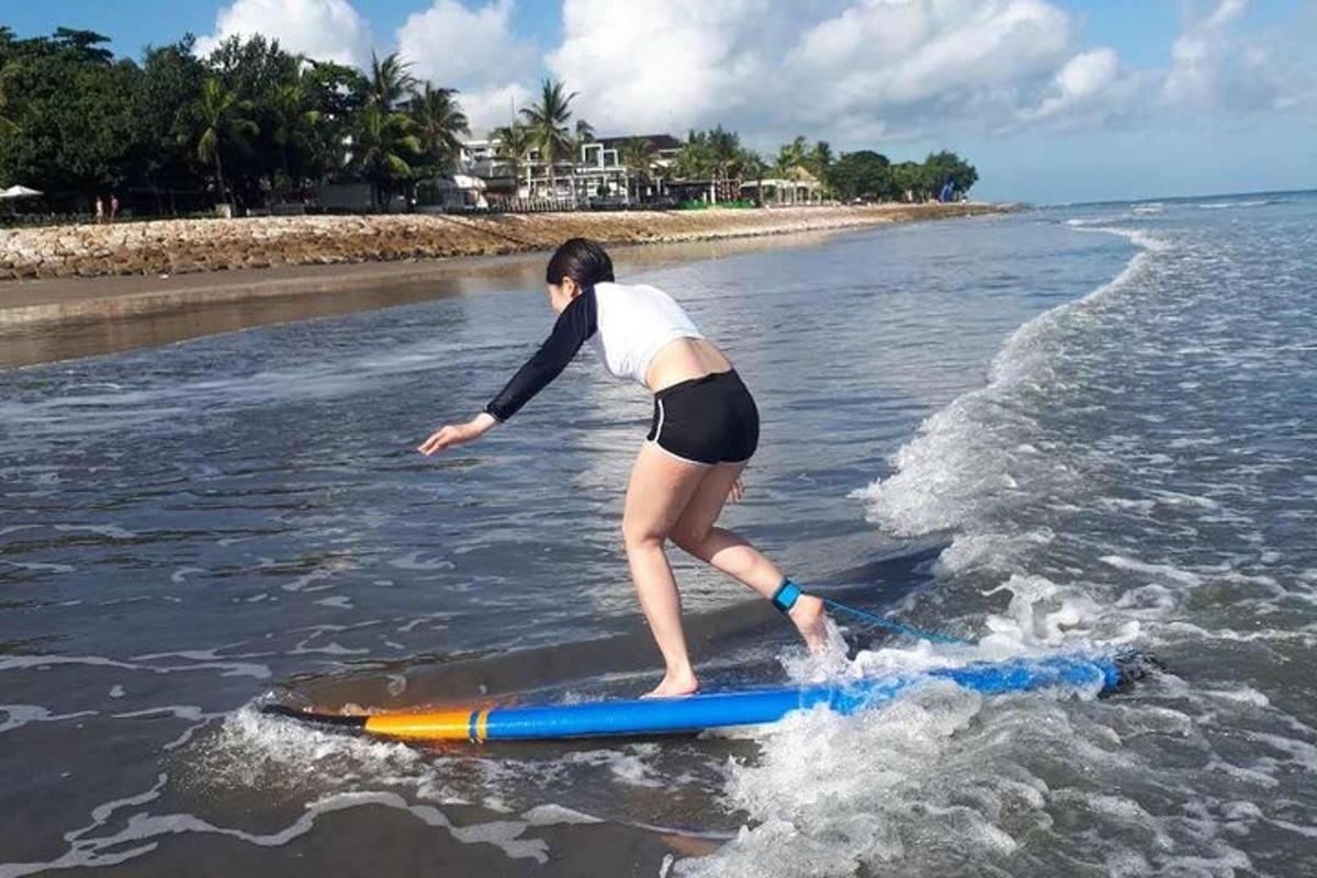 kobieta stojąca na desce surfingowej w wodzie