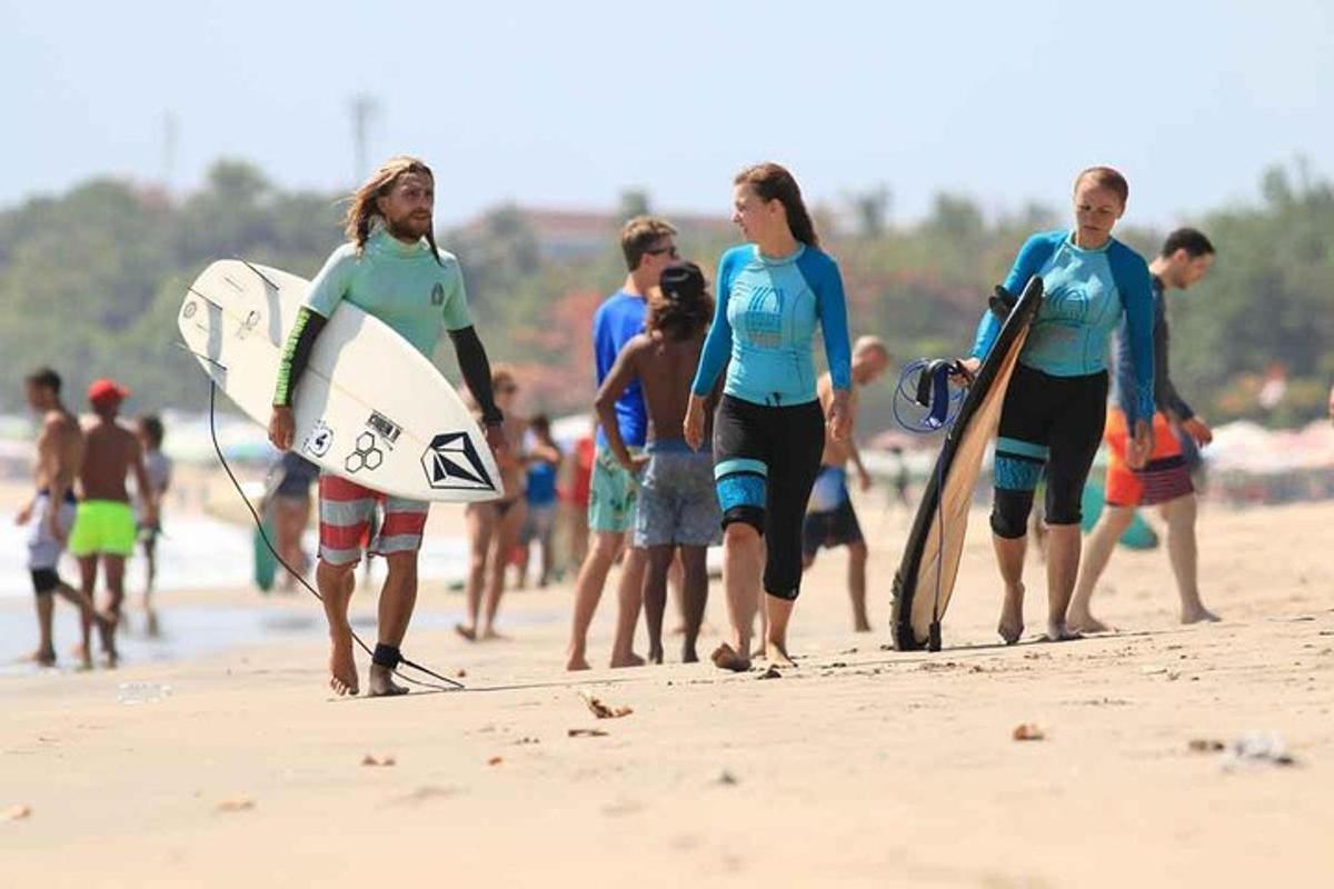 a group of people walking on the beach with surfboards