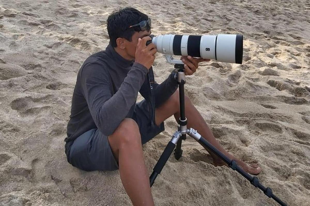 a man sitting on the beach with a camera