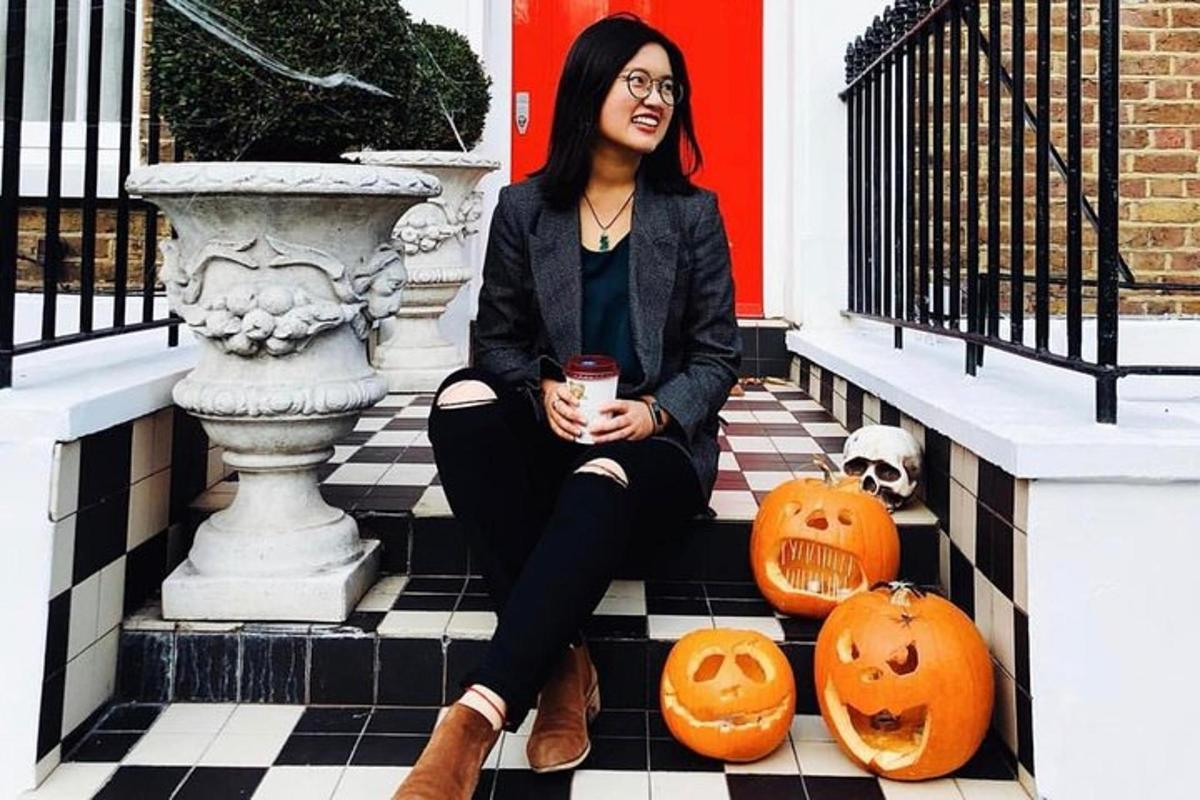 a woman sitting on the steps with pumpkins and a drink