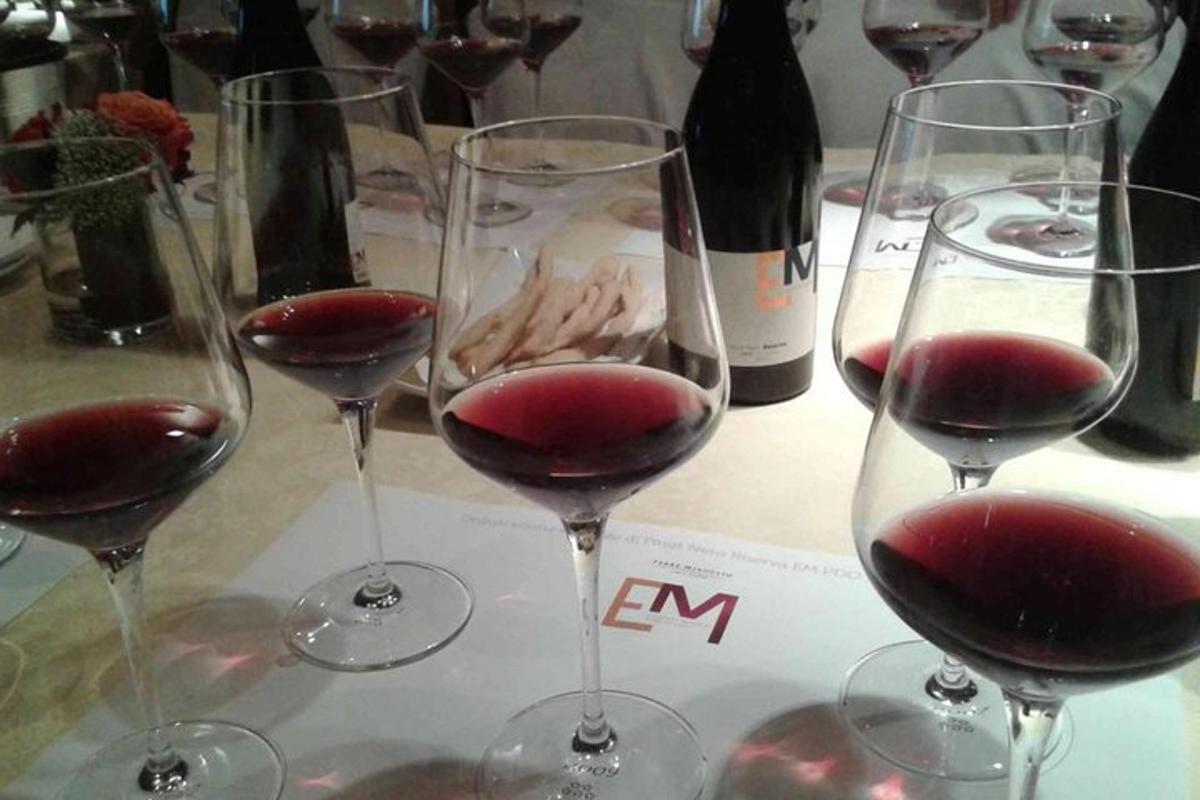 four glasses of red wine on a table with wine bottles