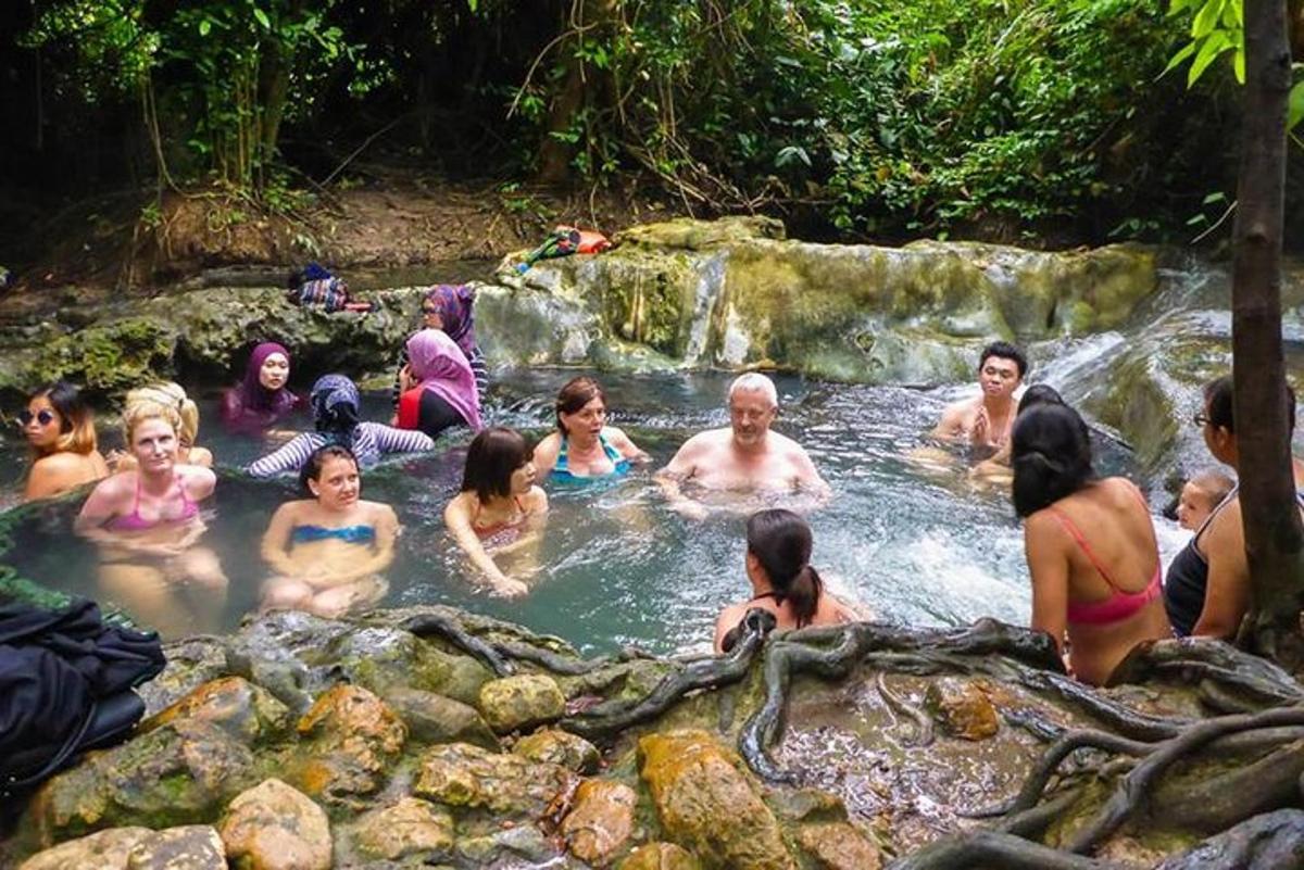 a group of people sitting in a hot tub next to a waterfall