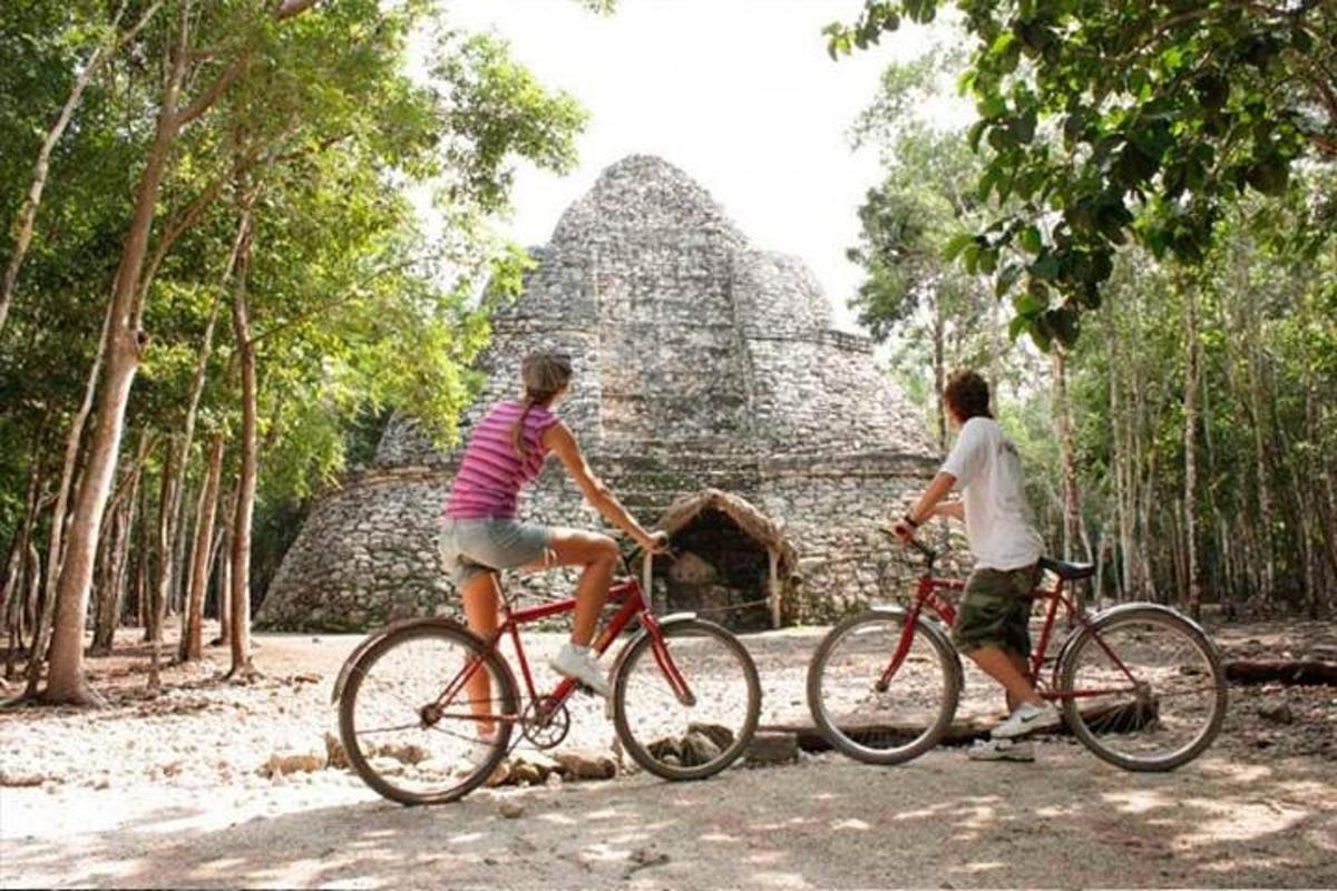 zwei Personen fahren Fahrrad vor einer Pyramide