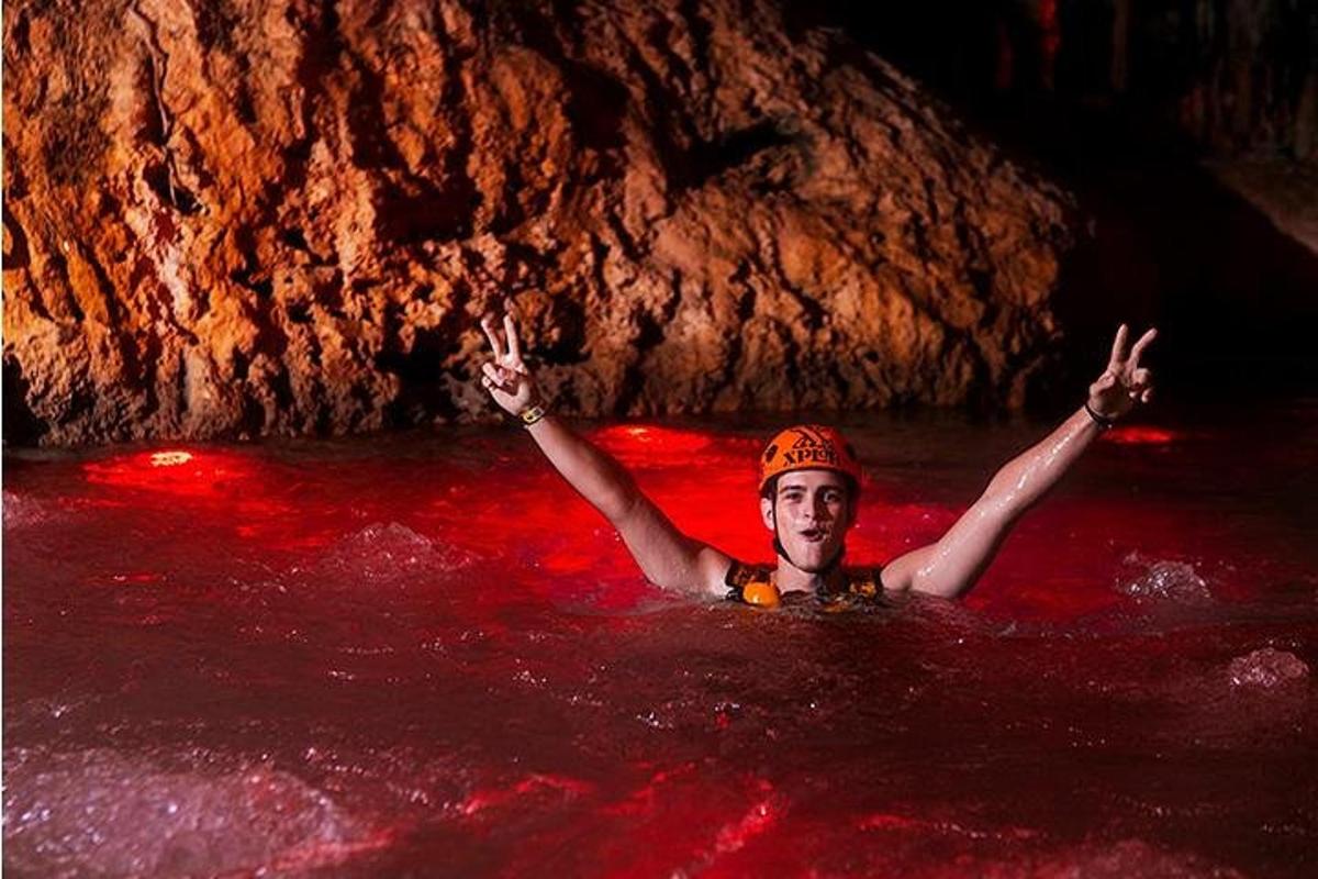 Un hombre en el agua con los brazos en alto en una cueva.