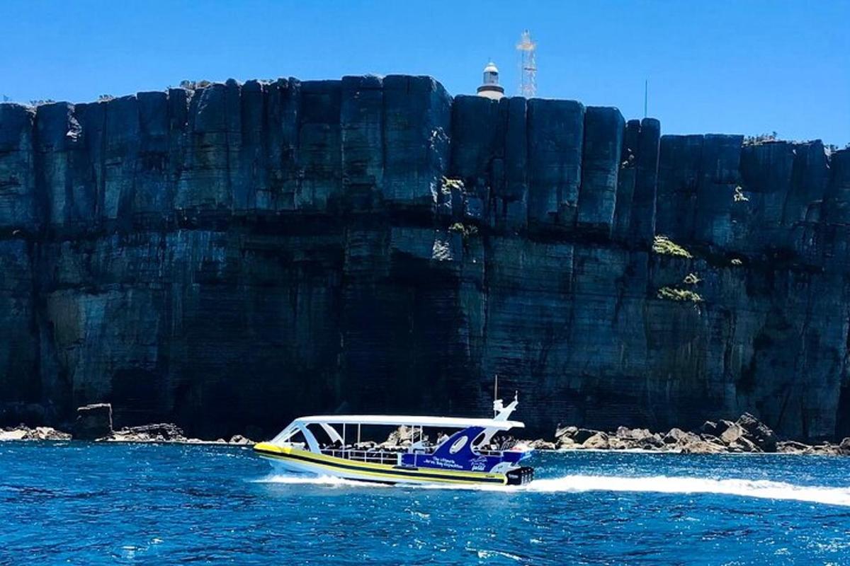 a boat in the water near a large rock wall