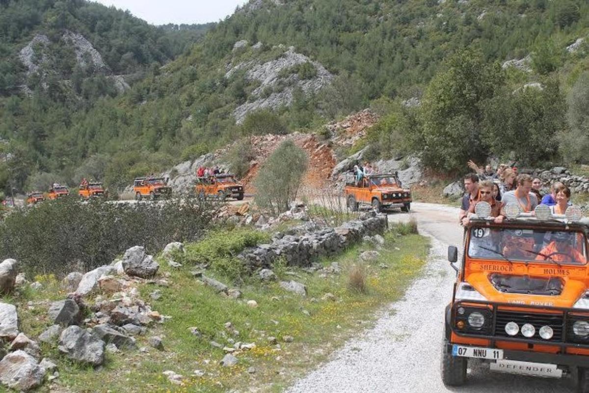 um grupo de pessoas andando de jipe em uma estrada de terra