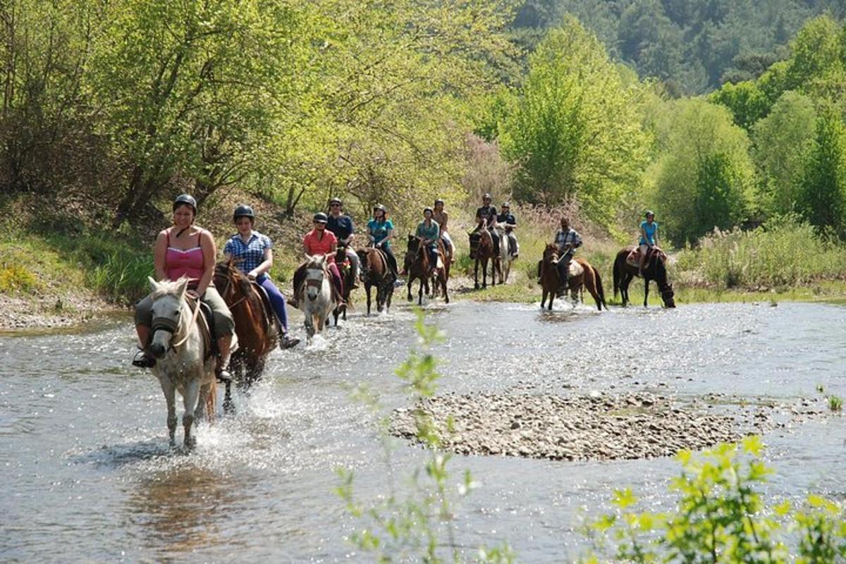 un grup de persones muntant a cavall per un riu