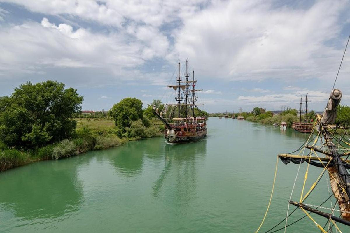 a large boat on a river with trees and clouds