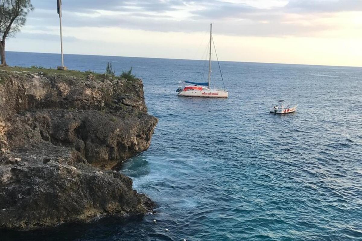 due barche che galleggiano sull'acqua accanto a una scogliera