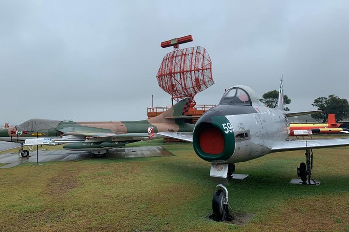 a fighter plane parked in a field with a cage on it