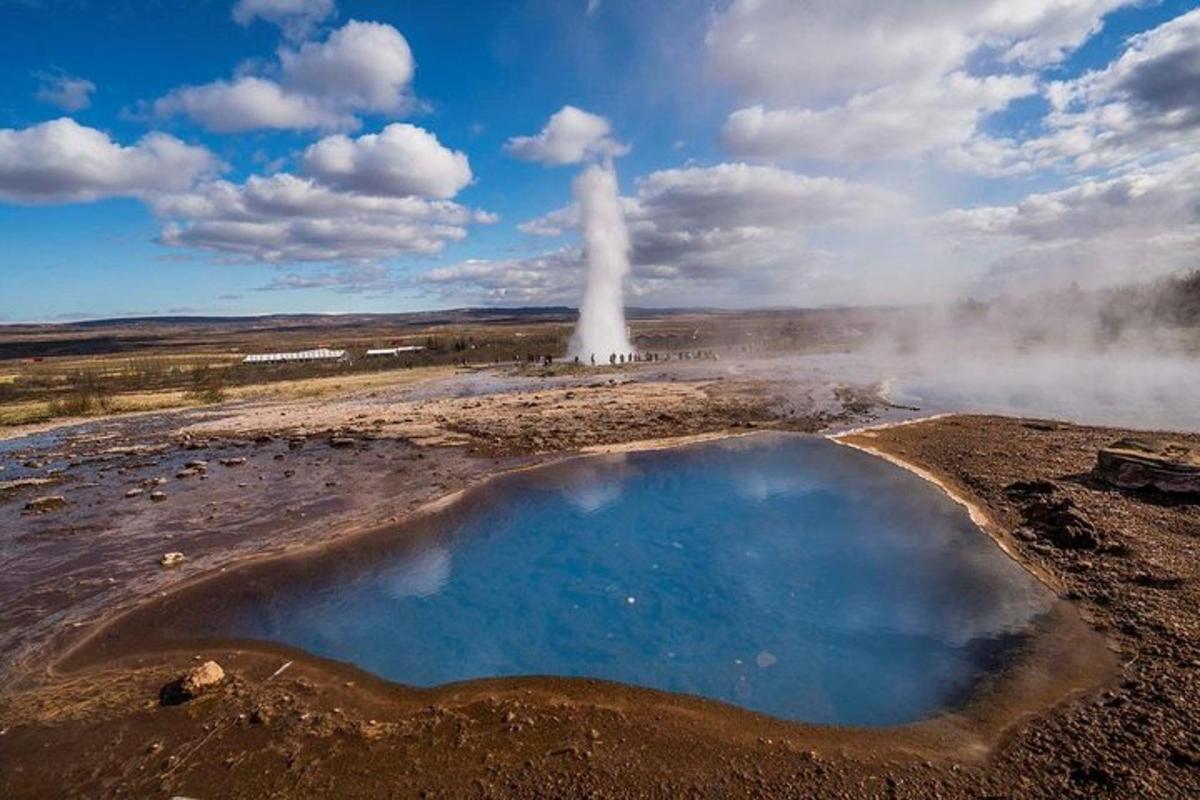 una sorgente termale con un geyser sullo sfondo