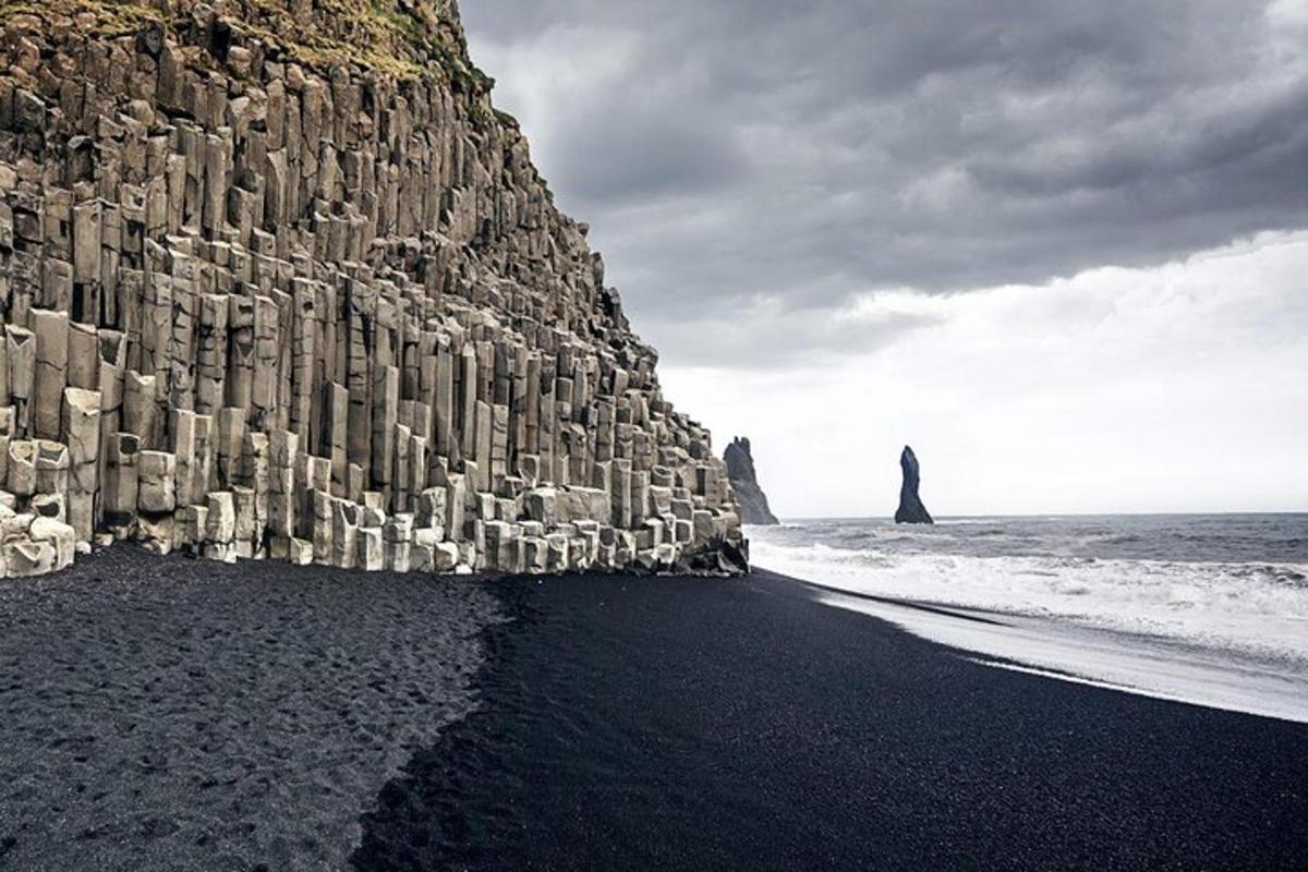 una parete rocciosa su una spiaggia nera con scogliere