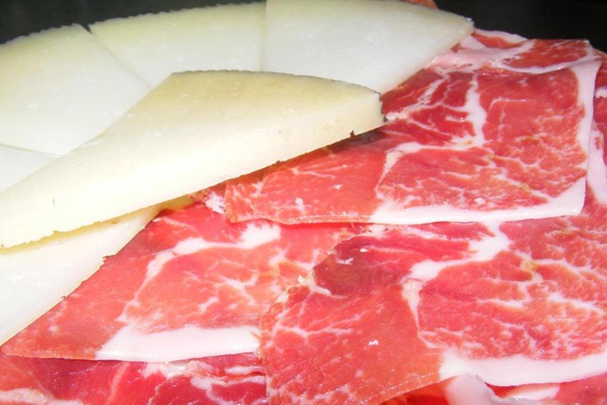 un gruppo di salumi e formaggi e un pezzo di formaggio