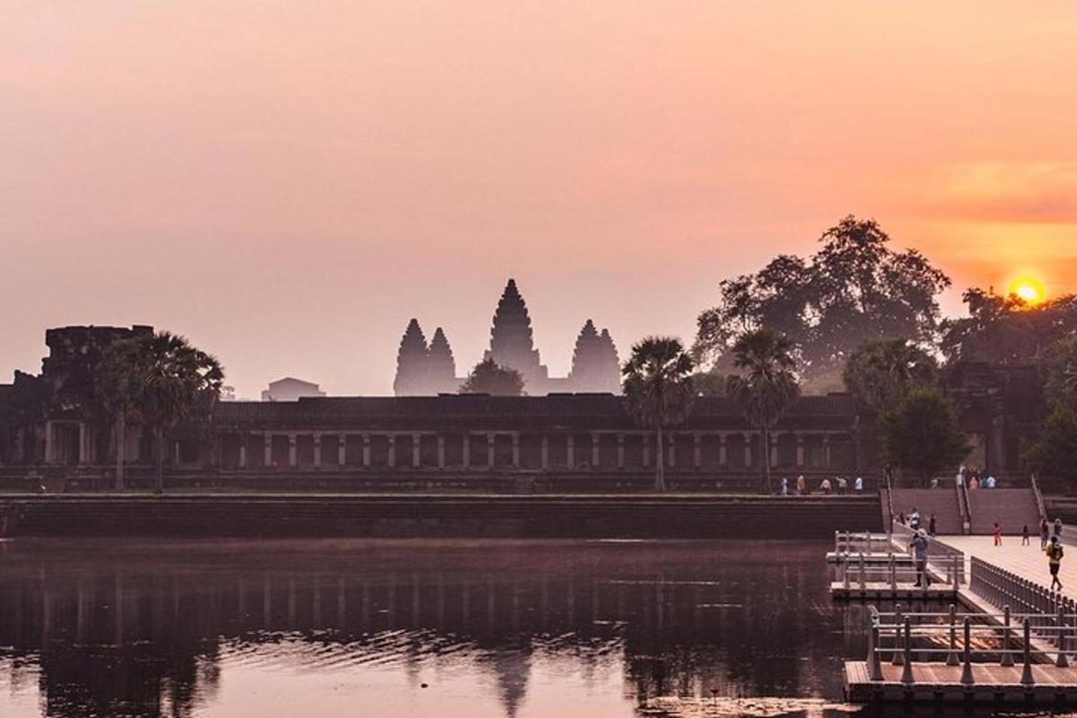 una posta de sol sobre un edifici al costat d'una massa d'aigua