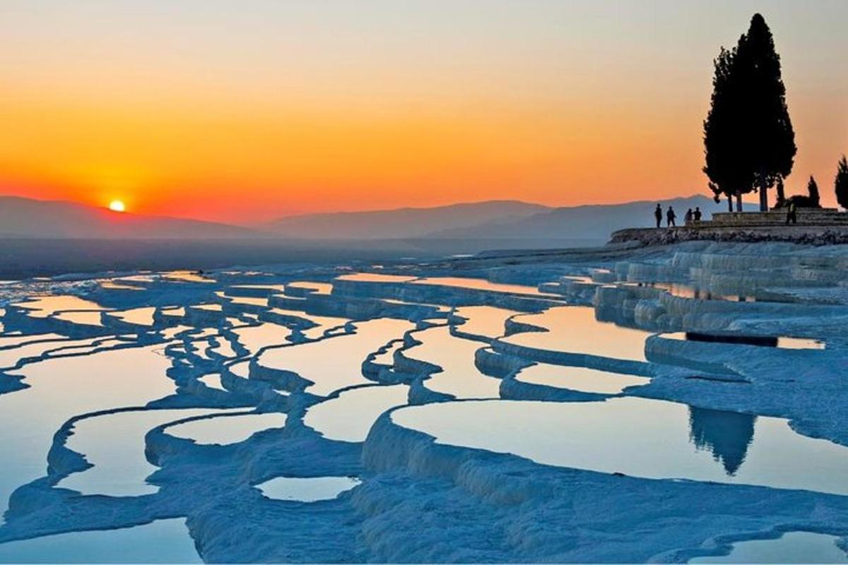 people standing on the shore of a river at sunset