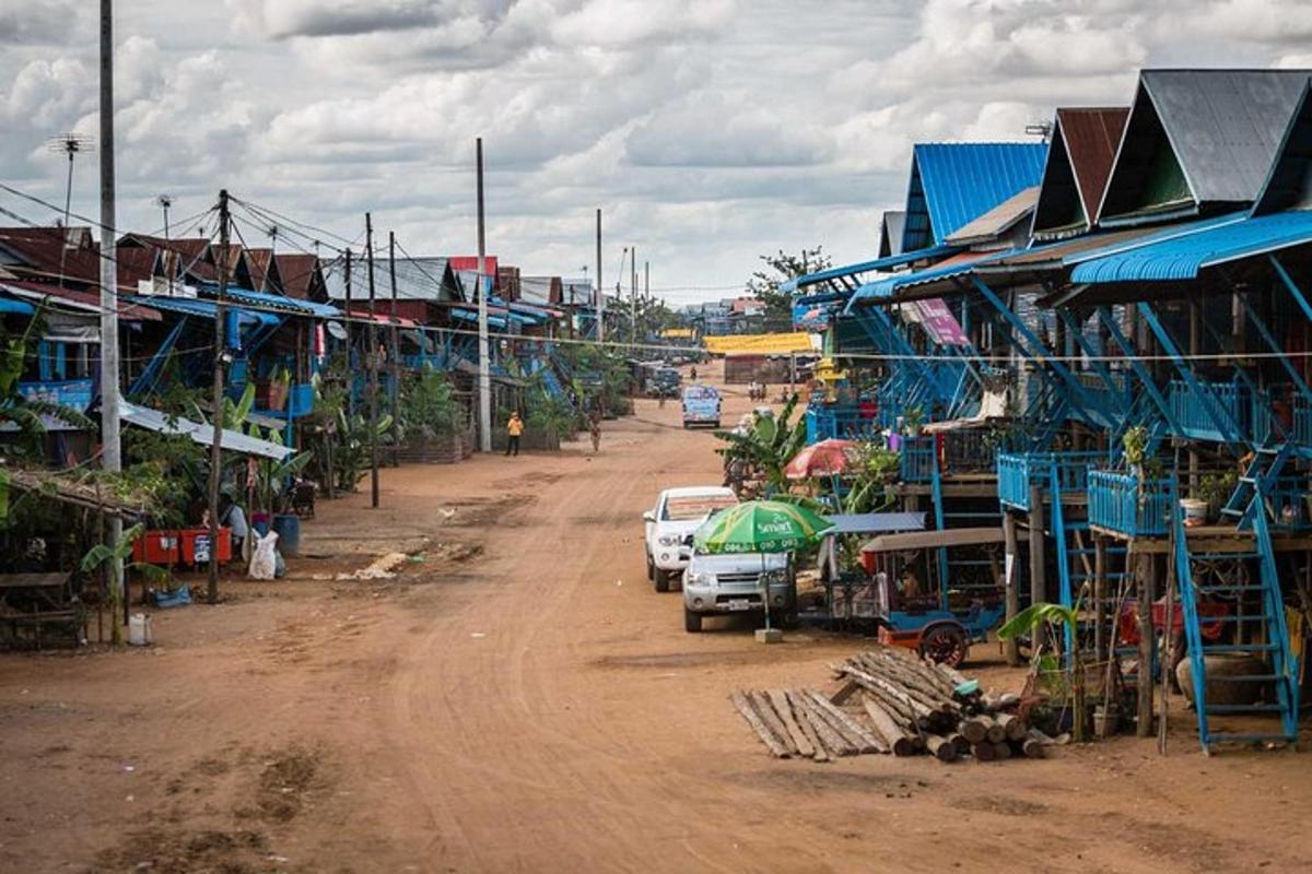 a dirt road next to a village with buildings