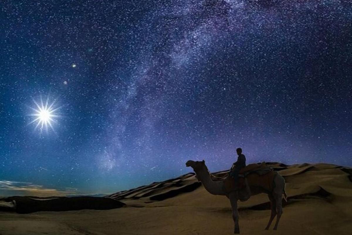 a man riding a camel in the desert under the stars