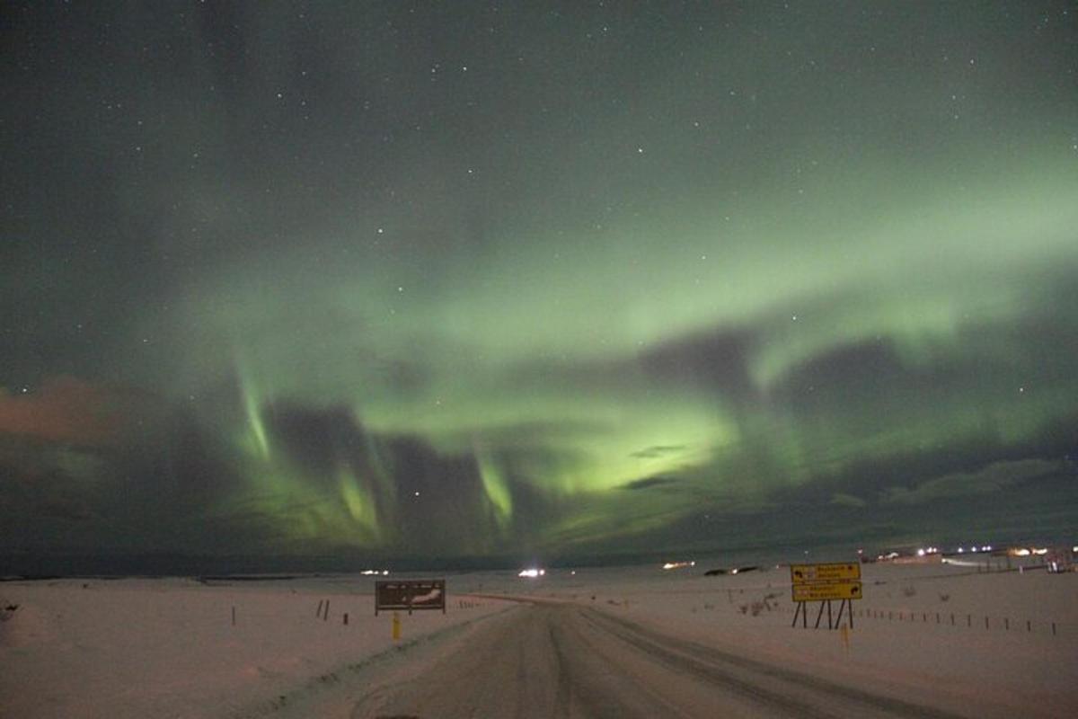 uma aurora no céu sobre uma estrada à noite