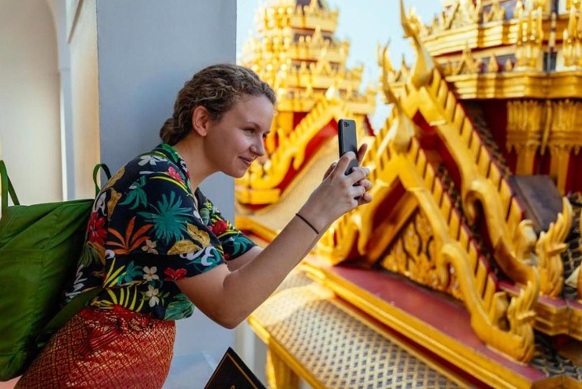 a woman taking a picture of a gold object with her cell phone