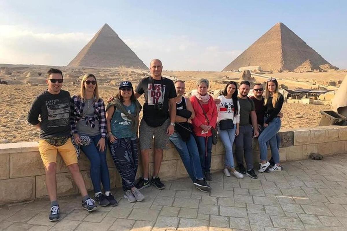 en gruppe mennesker som står på en vegg foran pyramider