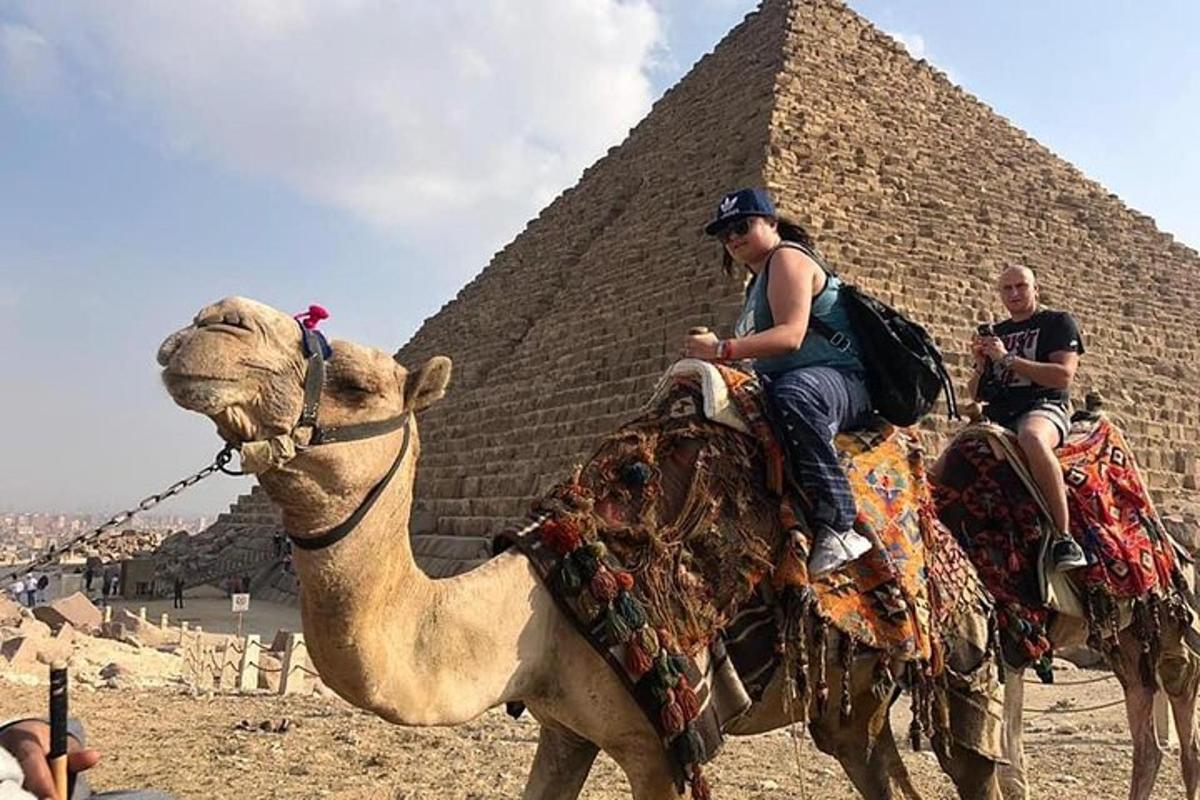 to personer som rir på en kamel foran en pyramide