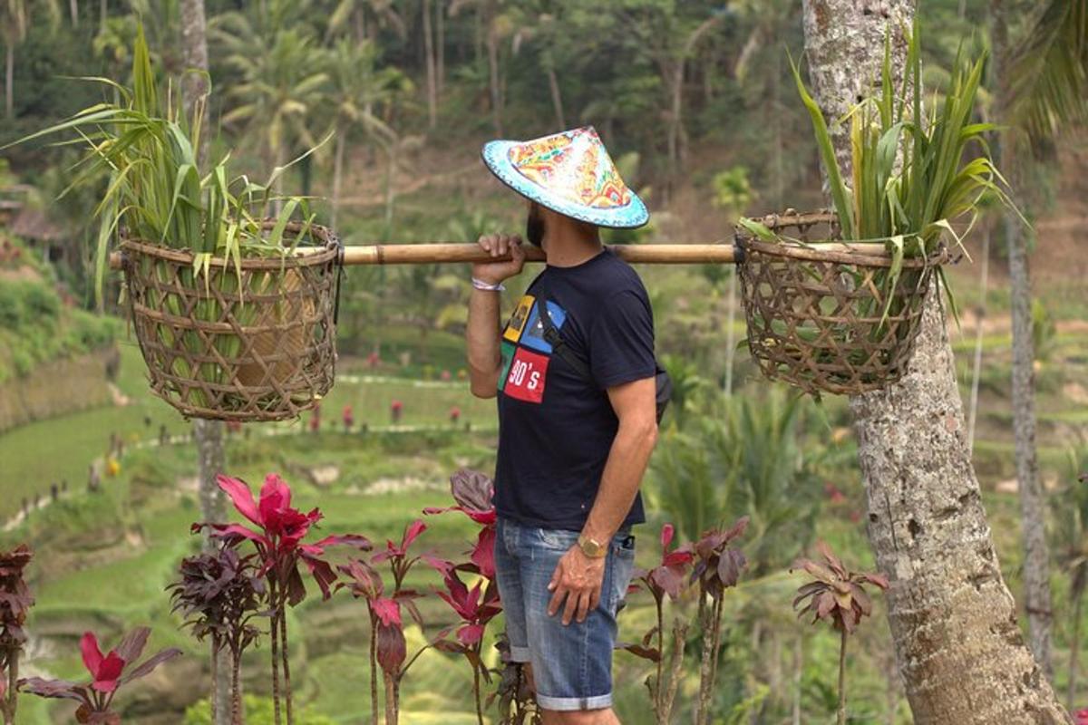 seorang lelaki memakai topi berdiri di sebelah dua pokok pasu
