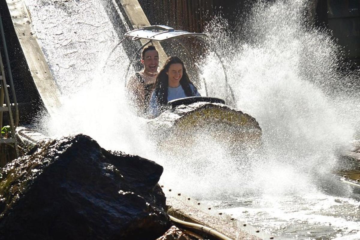 a man and a woman riding an elephant in a waterfall