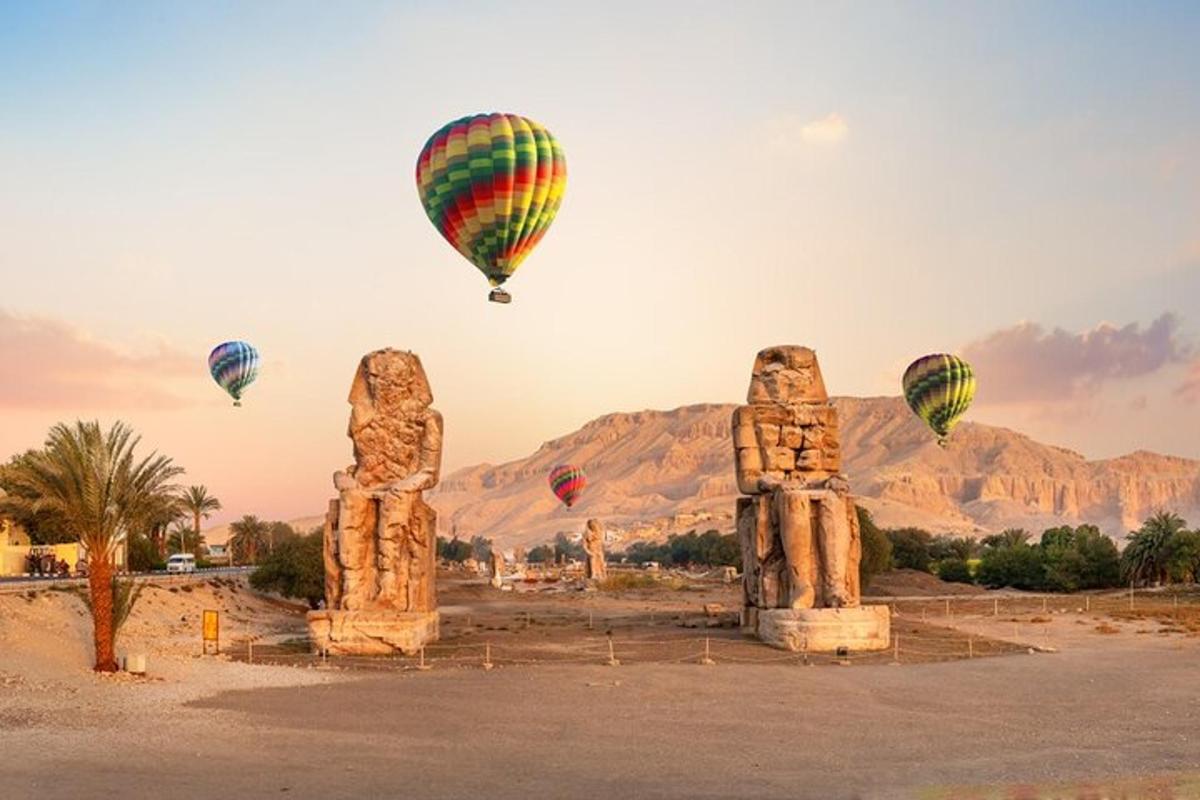 a group of hot air balloons flying over stone statues
