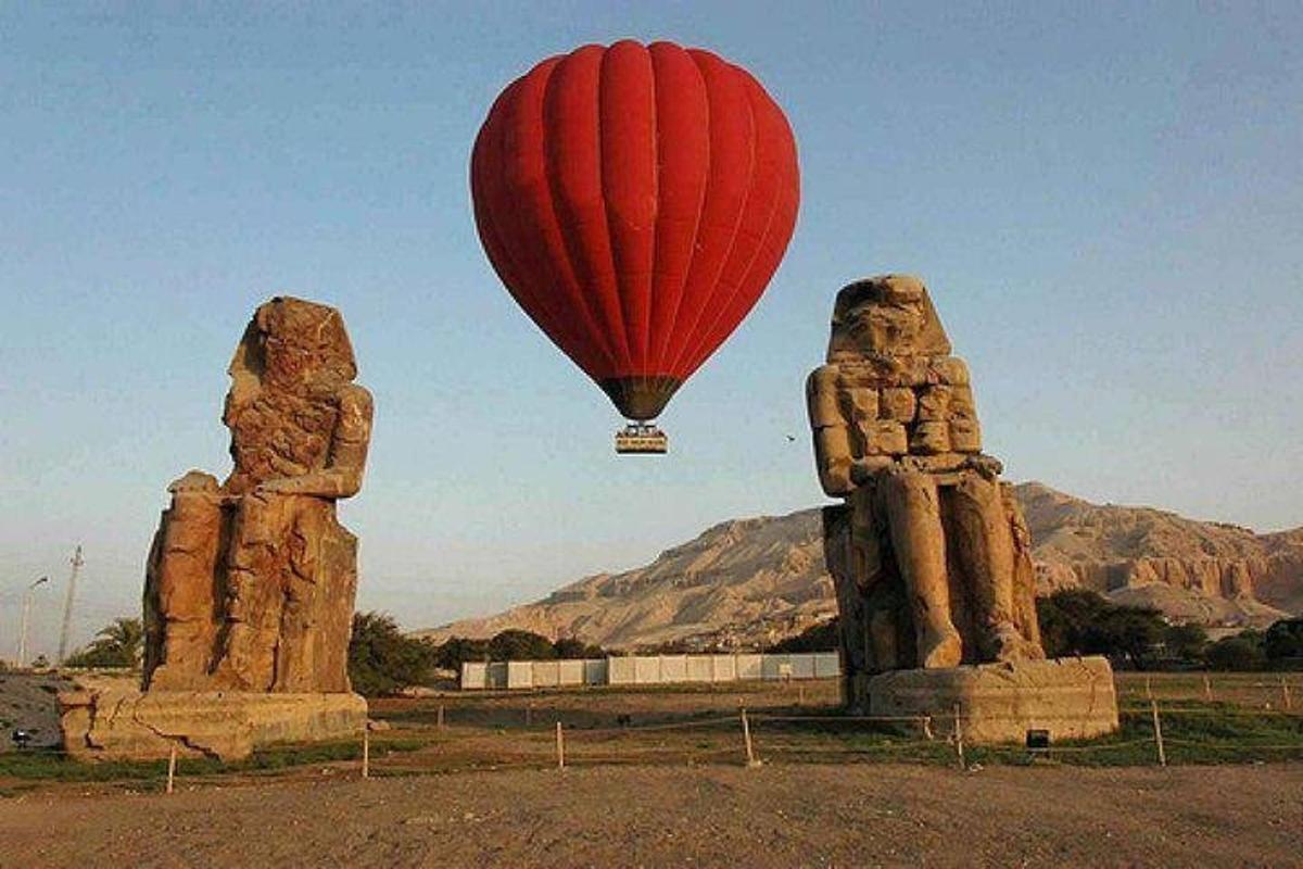 a hot air balloon flying over two statues