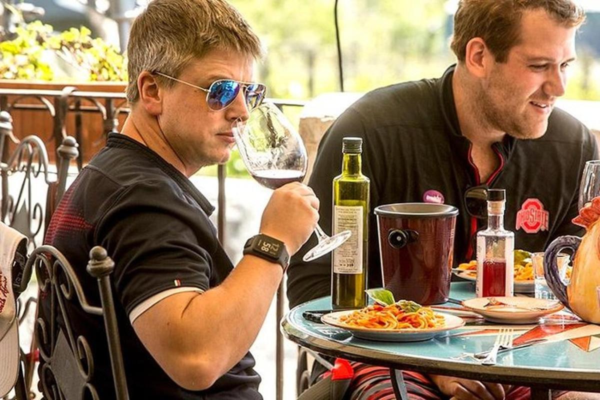 two men sitting at a table with a glass of wine