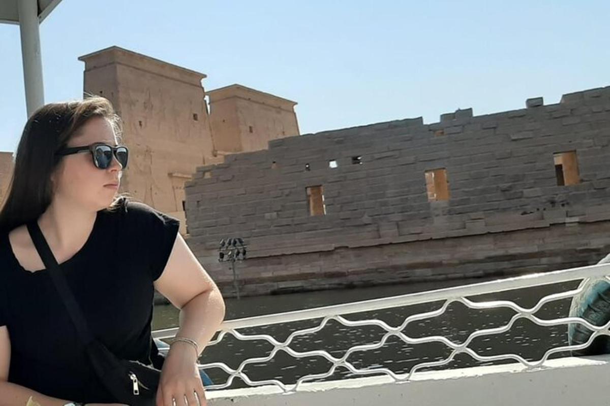 Una mujer con gafas de sol sentada en una cornisa