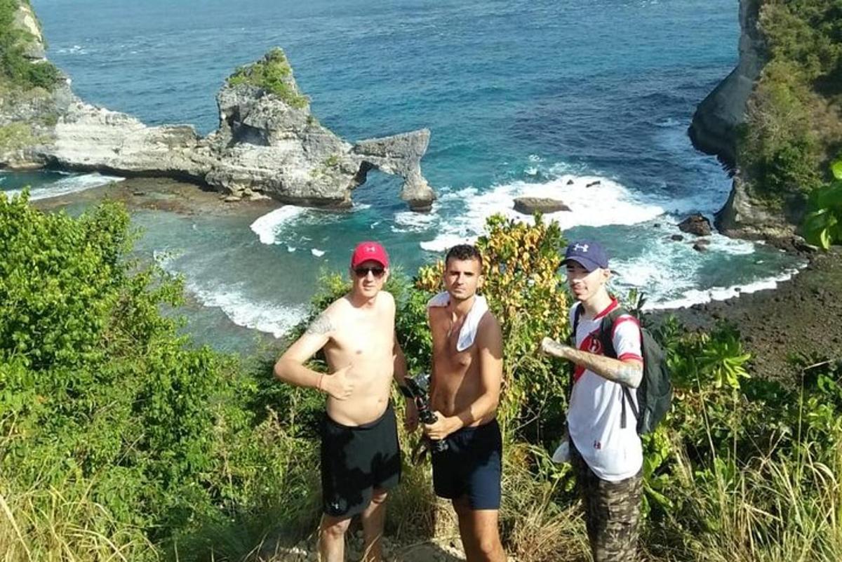 tři muži stojící na kopci poblíž oceánu