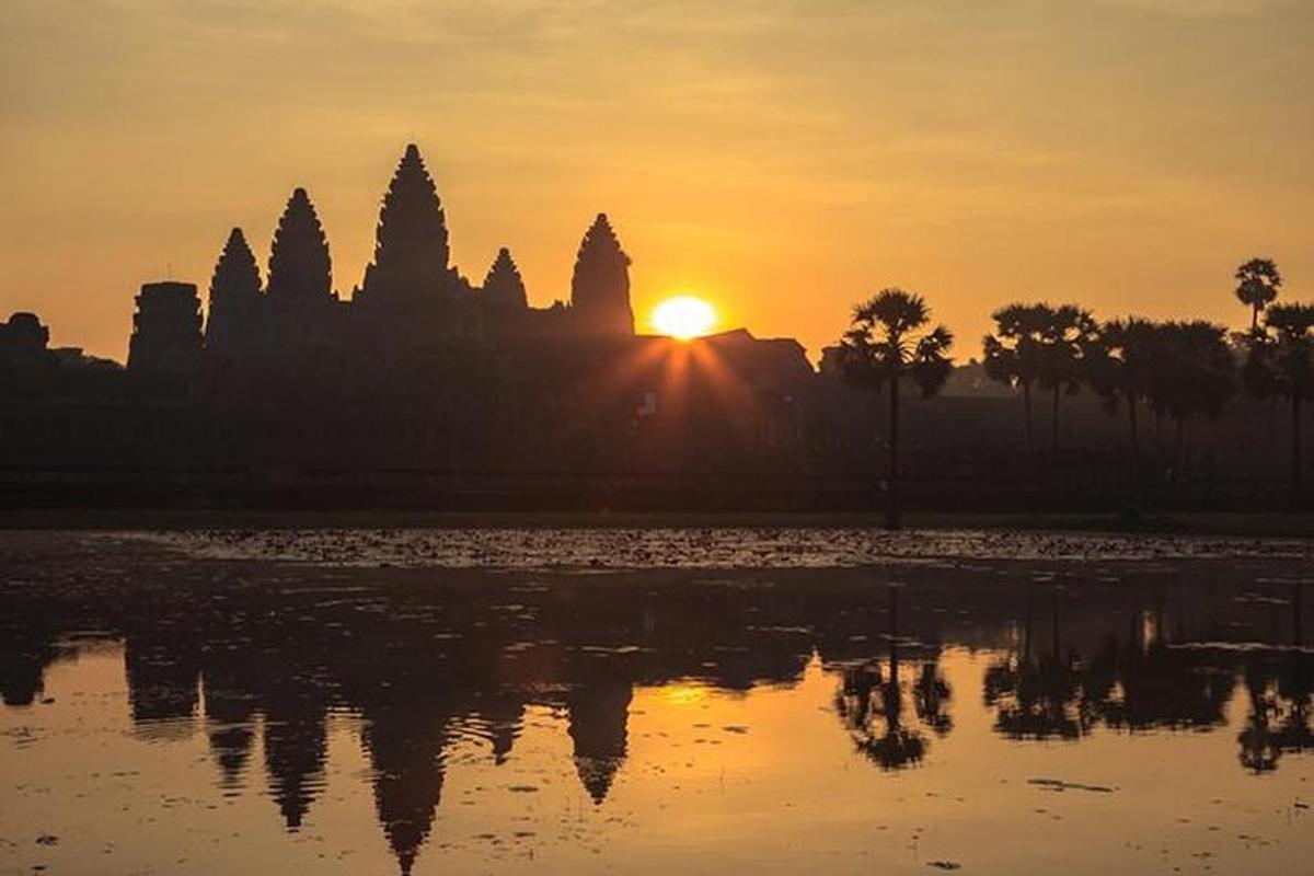 Una puesta de sol frente a un templo con un cuerpo de agua.