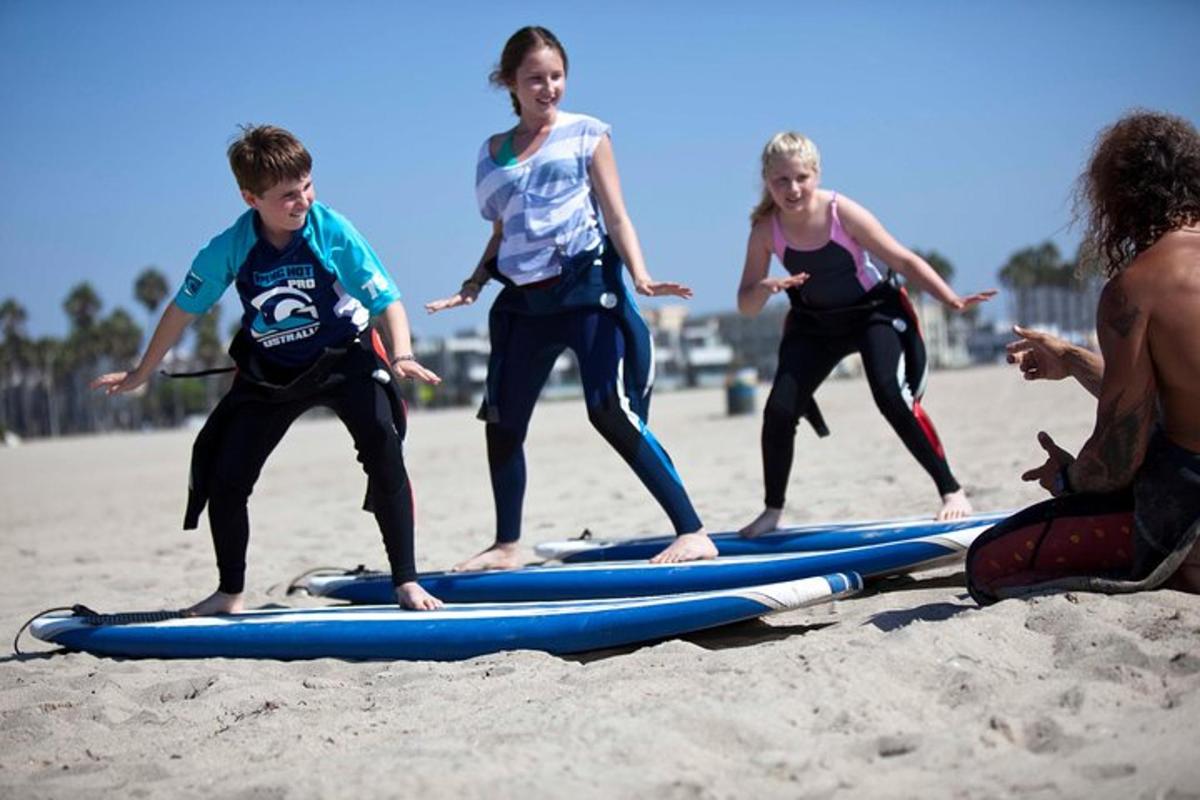 un grup de nens dempeus sobre taules de surf a la platja