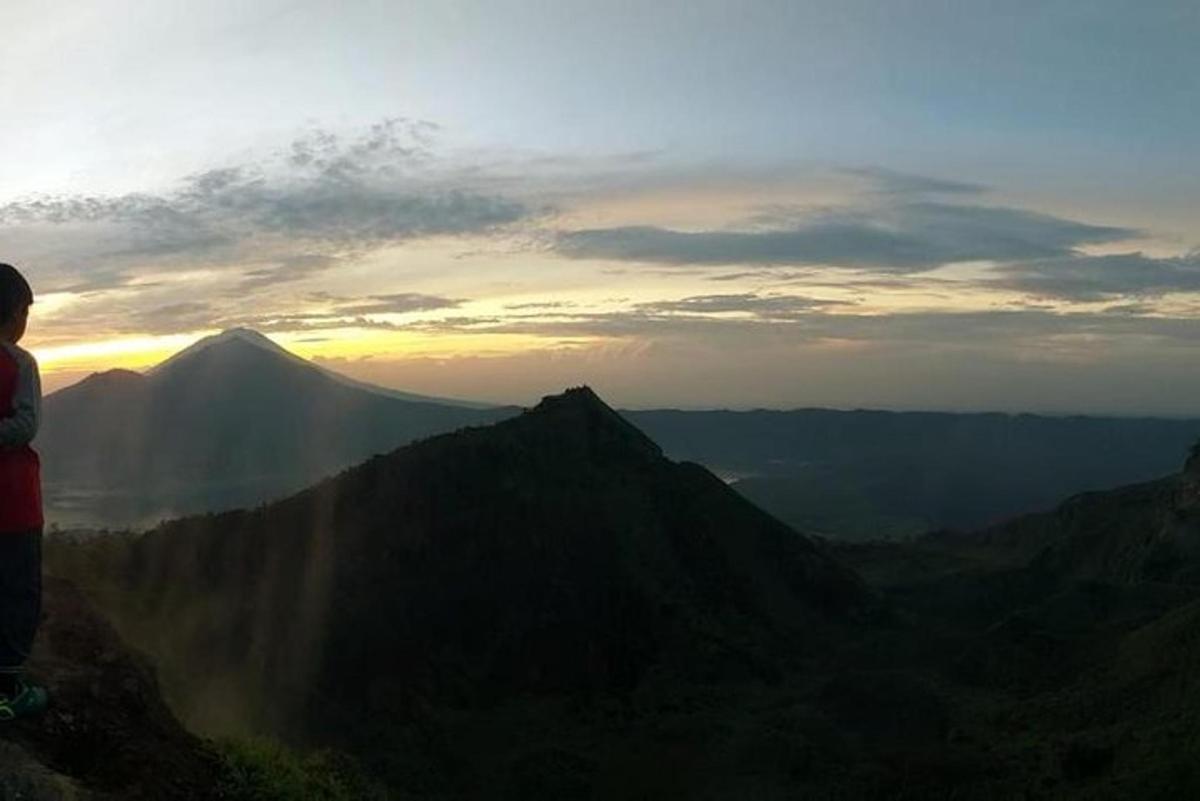 a person standing on top of a mountain looking at the sunset