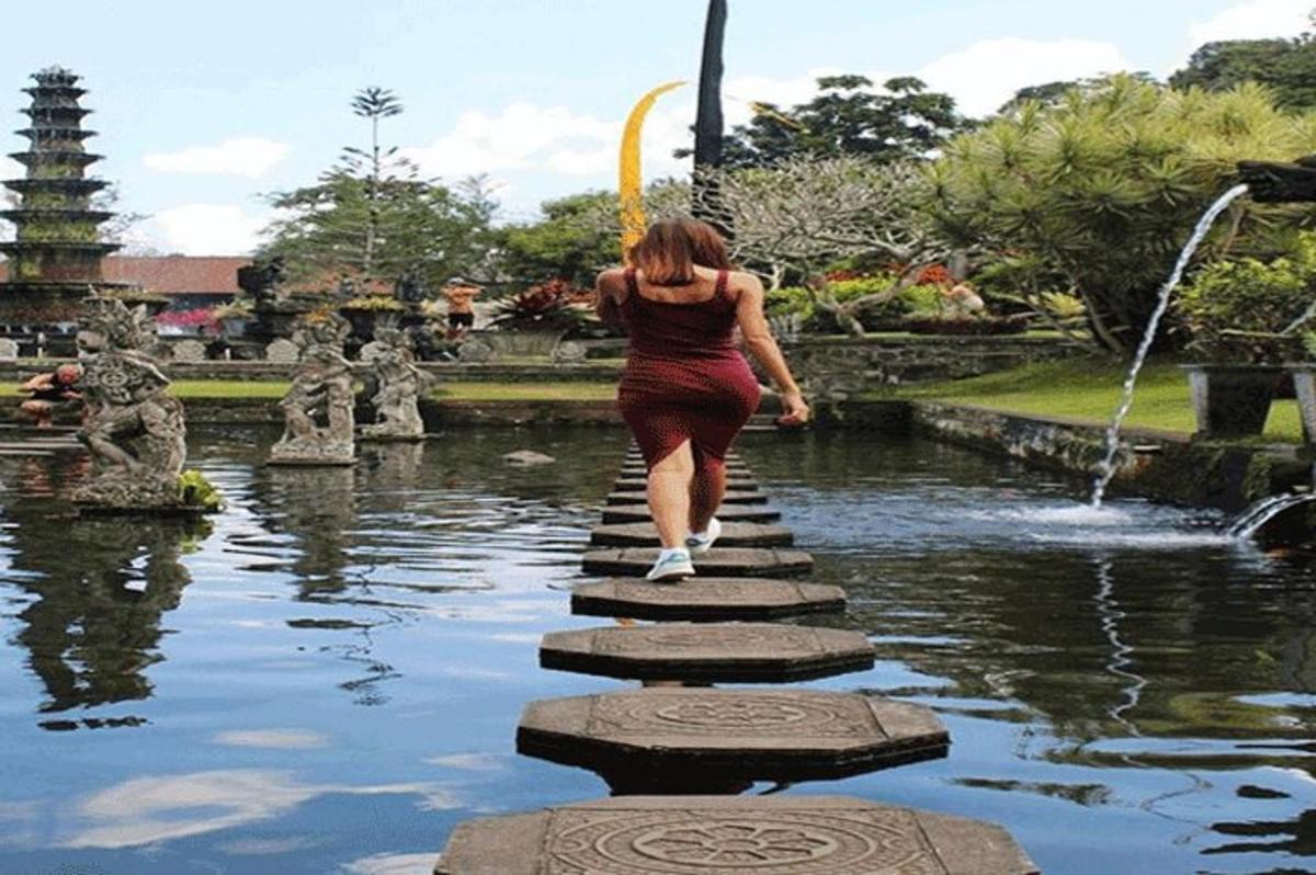 una donna che attraversa un ponte sopra uno stagno in un parco