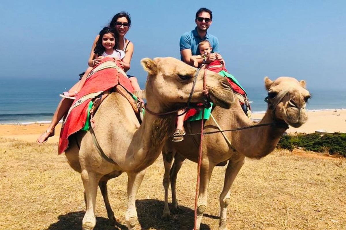 a group of people riding on the backs of camels on the beach