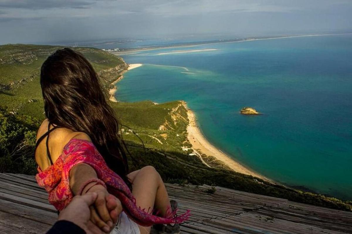 una donna seduta in cima a una collina che guarda l'oceano
