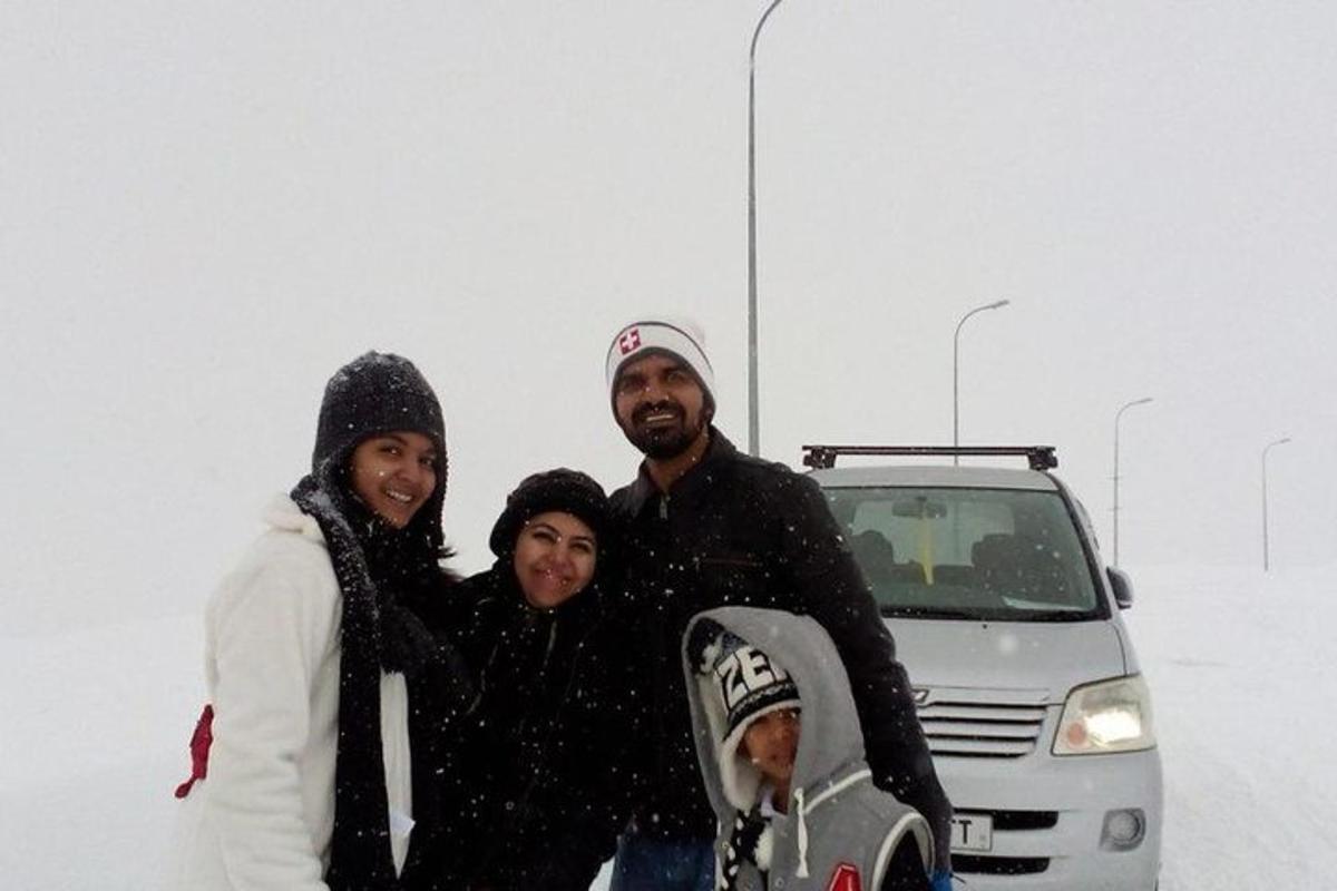 a group of people standing in the snow with a snowboard