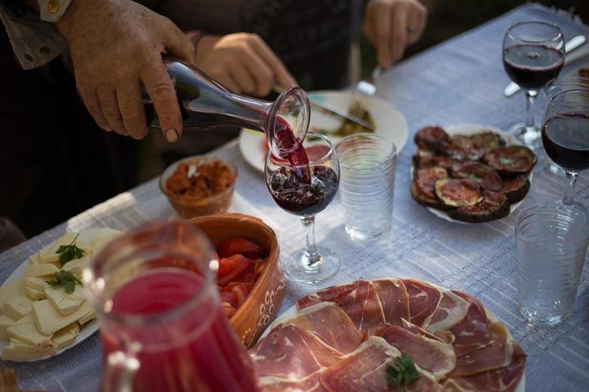 a person pouring a glass of wine on a table with food