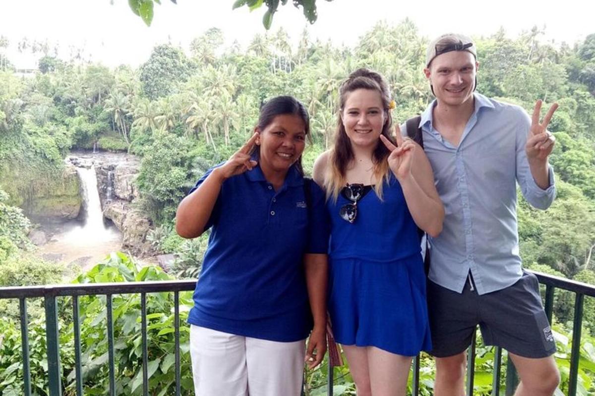 a group of three people standing in front of a waterfall